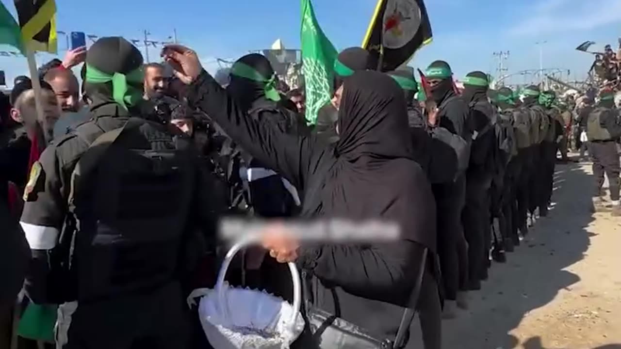 An elderly Palestinian woman sprinkles roses on the heads of the resistance fighters