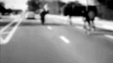 Car weaves through a group of cyclists