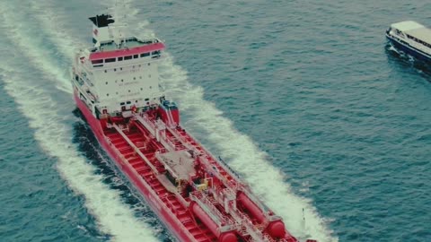 Aerial View of a Red Cargo Ship Sailing Through Open Waters