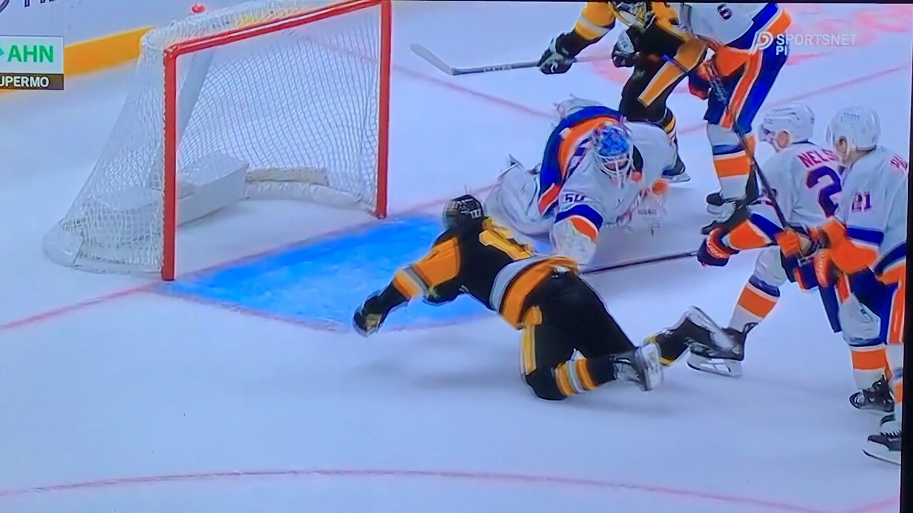 Islanders goalie #50 Marcus Hogberg stops Penguins #17 Bryan Rust with his stick.