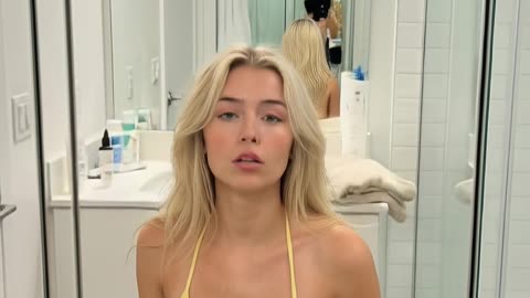 Pretty girl in a bikini sits in front of a mirror