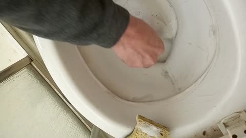 Guy with a pumice stone working on neglected toilet