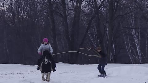 Little Snowboarder Pulled by Pony-Riding Sister