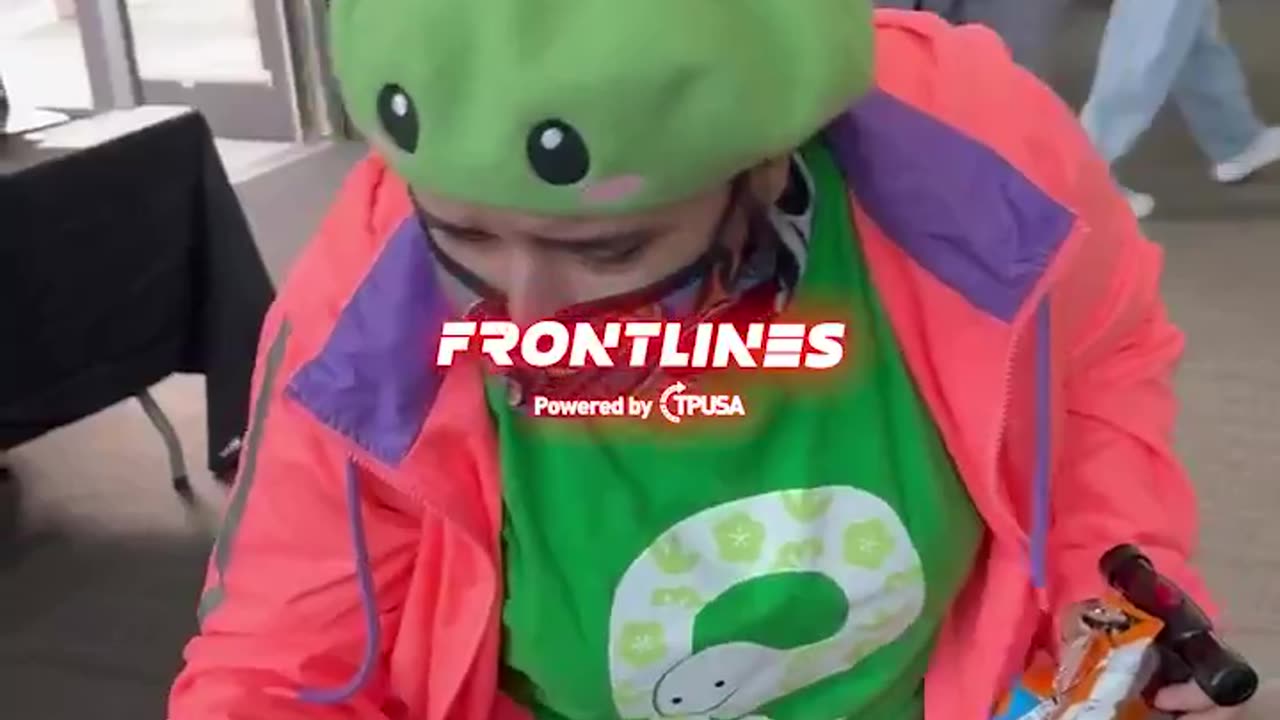 An unidentified masked agitator pours soda on a @TPUSA table display after reportedly