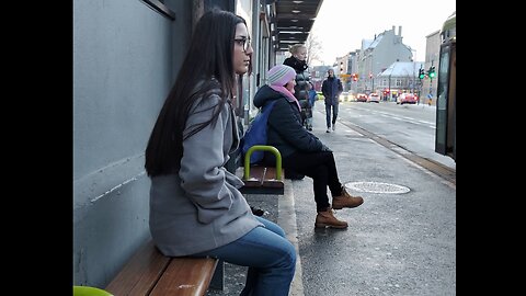 Beautiful woman freezing winter frost of real feel -16°C. Light teeth chattering and shivering cold