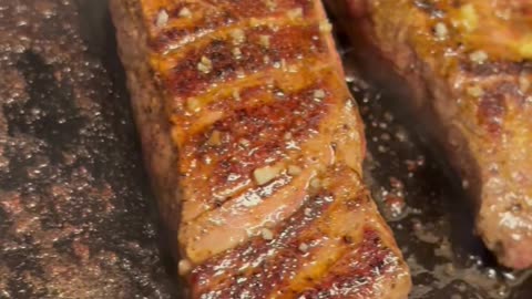 Flank Steaks Sizzling on Cast Iron