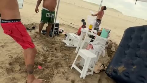 Beachgoers Fight Storm to Keep Their Canopy