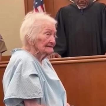 She's 91 years old, standing in a hospital gown, hands in chains