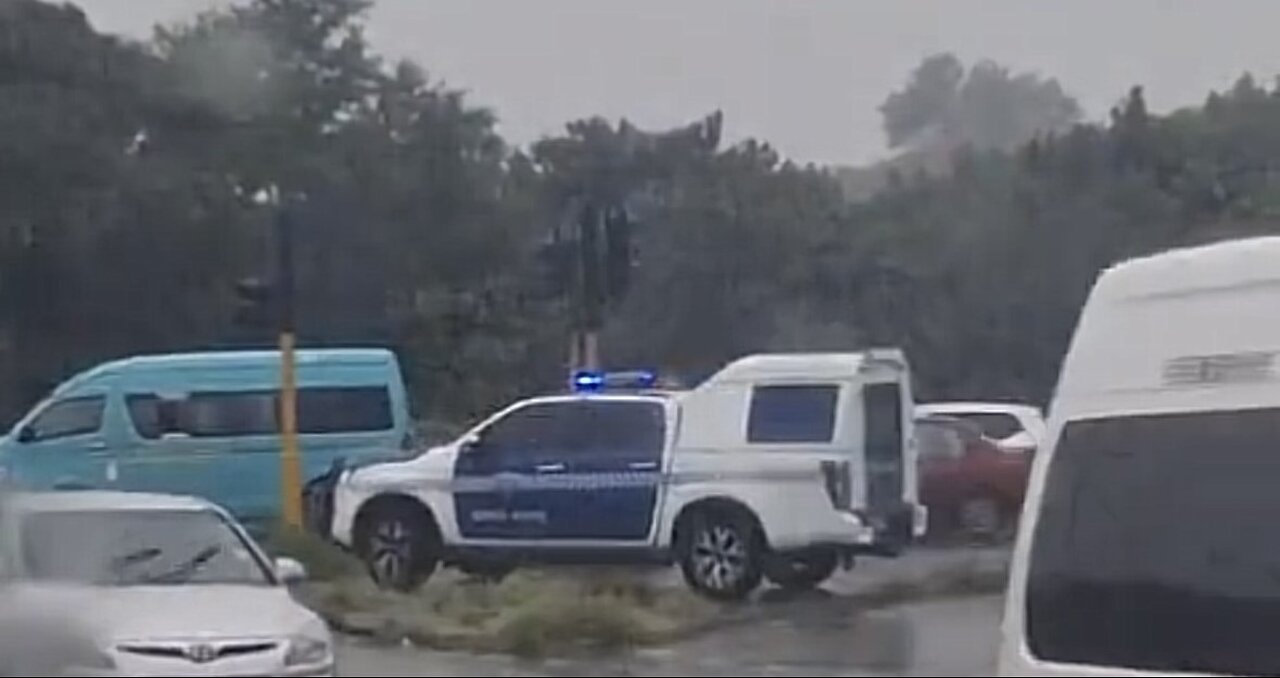 Durban Metro Police sit in vehicle as beggars direct traffic in the rain