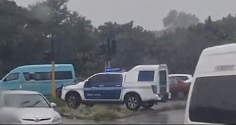 Durban Metro Police sit in vehicle as beggars direct traffic in the rain