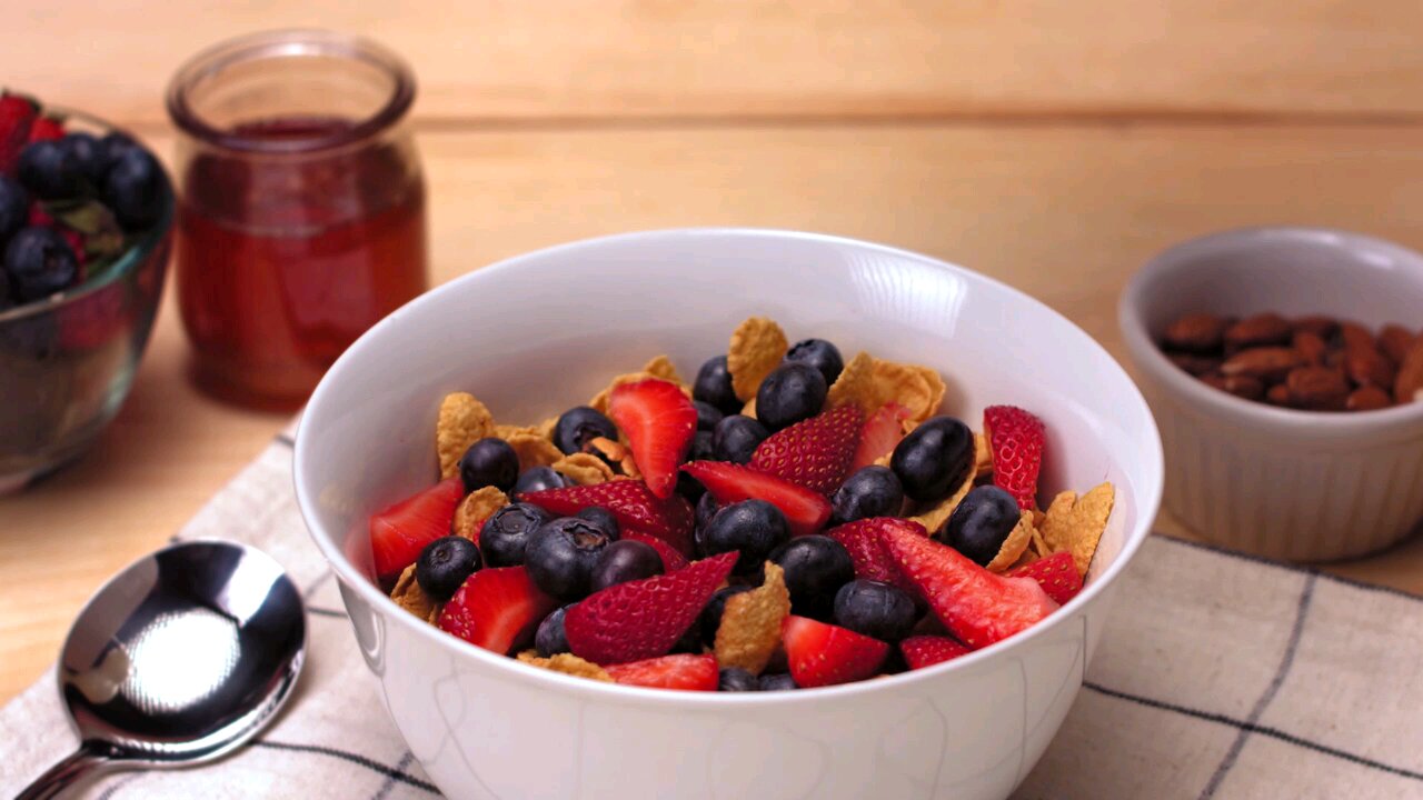 A continuous stream of pristine white milk falling and splashing into a bowl full of corn flakes,
