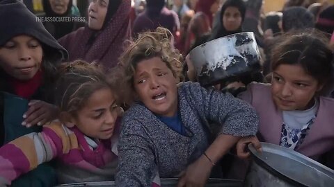 Displaced Palestinians wait for food at a makeshift charity kitchen in Khan Younis