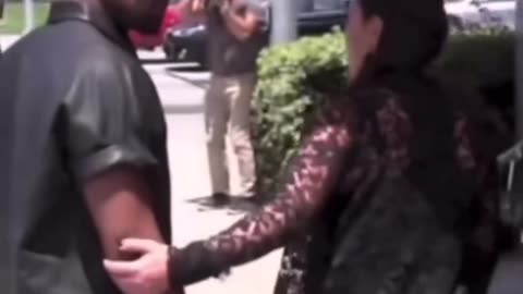 Kanye West and Kim Kardashian walking kanye hit the stop sign looking down while walking.