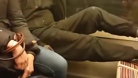 On a Paris train, a migrant smokes a cigarette and sets his bare feet on an opposite seat.