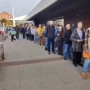 W 2025 roku ludzie w Wielkiej Brytanii stoją w kolejce przed centrum medycznym, czekając na swoją dawkę szczepionki.