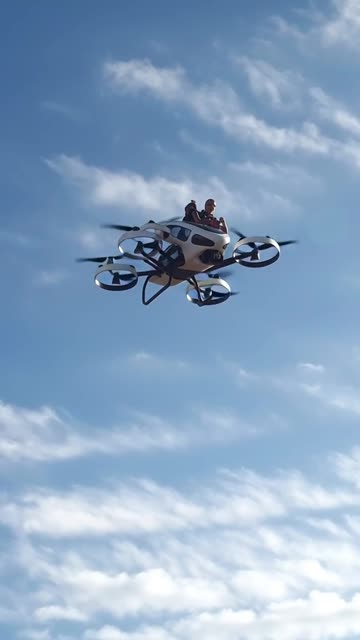 a exact copy of drone into a flying car in the sky with2 people in it with other drone flying