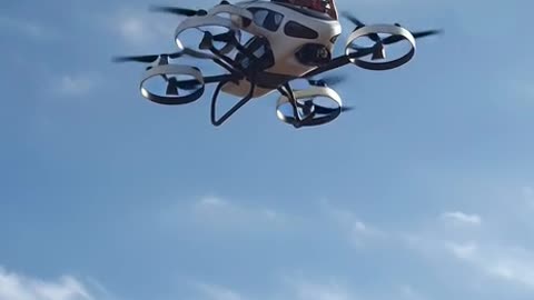 a exact copy of drone into a flying car in the sky with2 people in it with other drone flying