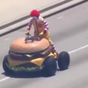 Ronald McDonald driving a hamburger car down the road for shits and giggles