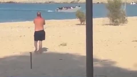 Tourists in Greece push a migrant boat back out to sea!