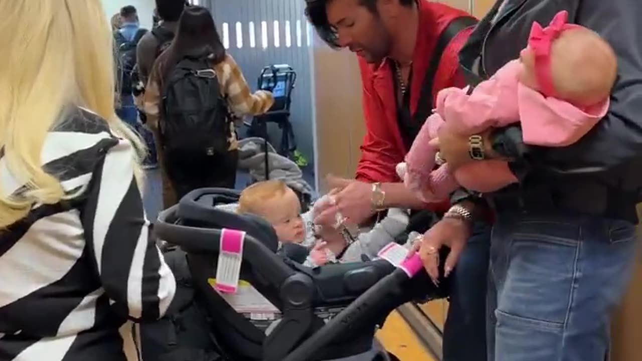 LGBTQI+ influencer shows off designer surrogate baby with husband at airport.