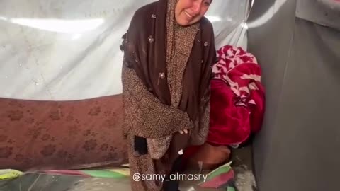 A displaced Palestinian woman cries out as rainwater floods her tent in Gaza