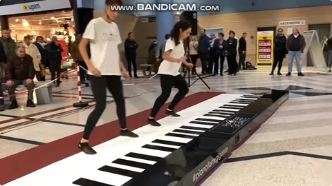 two girls play a very big piano together