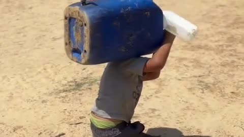 A disabled child in Gaza crawls on the ground, struggling to carry a water container