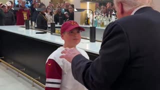 President Trump hands a young boy his presidential challenge coin while leaving the Commanders game