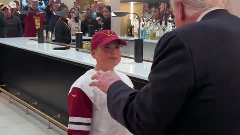 President Trump hands a young boy his presidential challenge coin while leaving the Commanders game