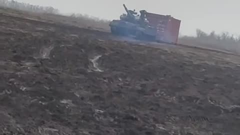 Russian T62 Tank Dragging Shipping Container Across Field, Probably for Fortifications