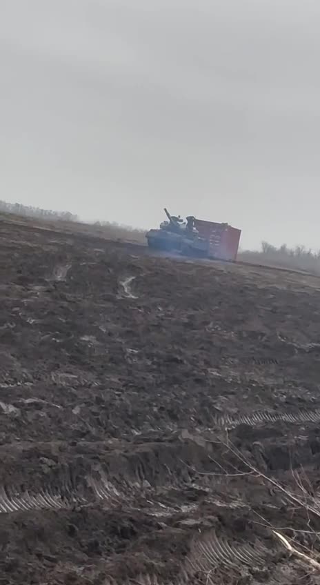 Russian T62 Tank Dragging Shipping Container Across Field, Probably for Fortifications