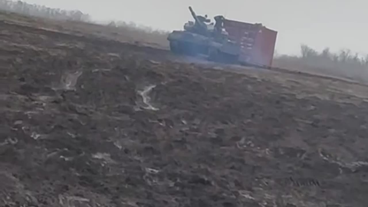 Russian T62 Tank Dragging Shipping Container Across Field, Probably for Fortifications