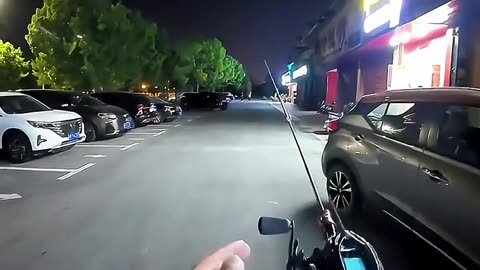 The man is fishing on the street with a fishing rod.🤣🤣🤣