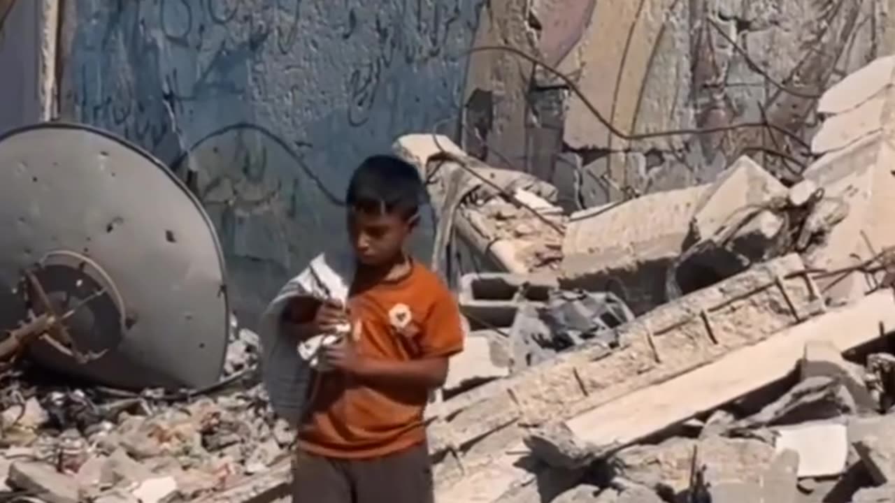 A boy walks through the rubble, carrying a worn-out bag on his shoulder to gather scraps of firewood
