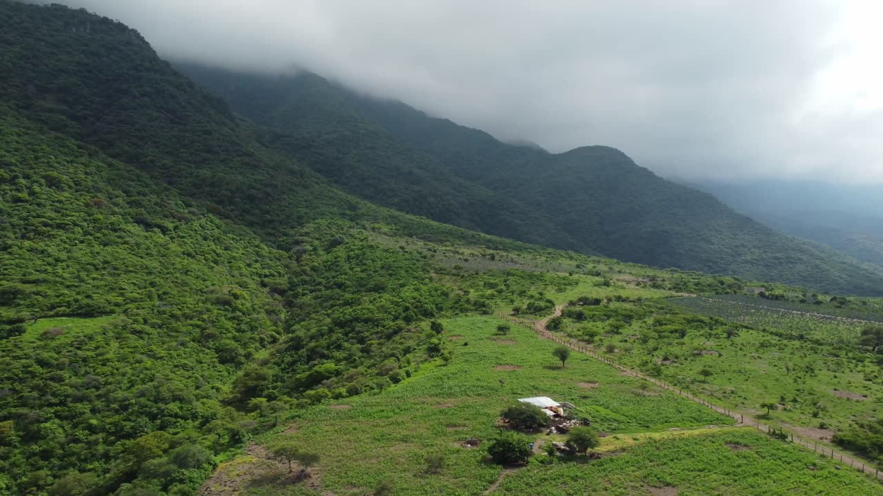 Lush green valley with mountains and cloudy sky