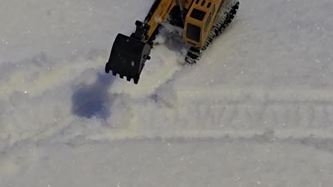 Miniature Excavator Works To Clear Snowfall