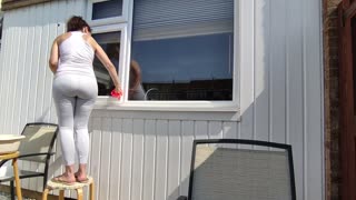 Cleaning Window Outdoors in Yoga Outfit