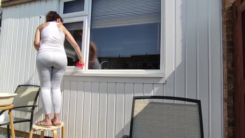 Cleaning Window Outdoors in Yoga Outfit