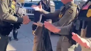 Commander Bovino playing rock paper scissors while the mob and impede caravan are honking
