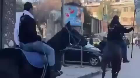 Islamists on horseback carry a jihadist flag into the Christian district of