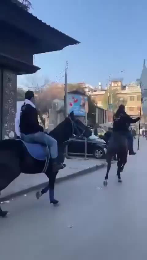 Islamists on horseback carry a jihadist flag into the Christian district of