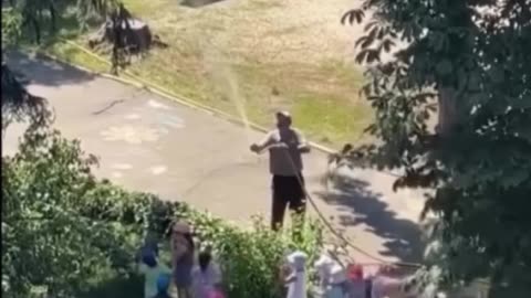 An elderly man created his own rainfall for a group of kids to play in.