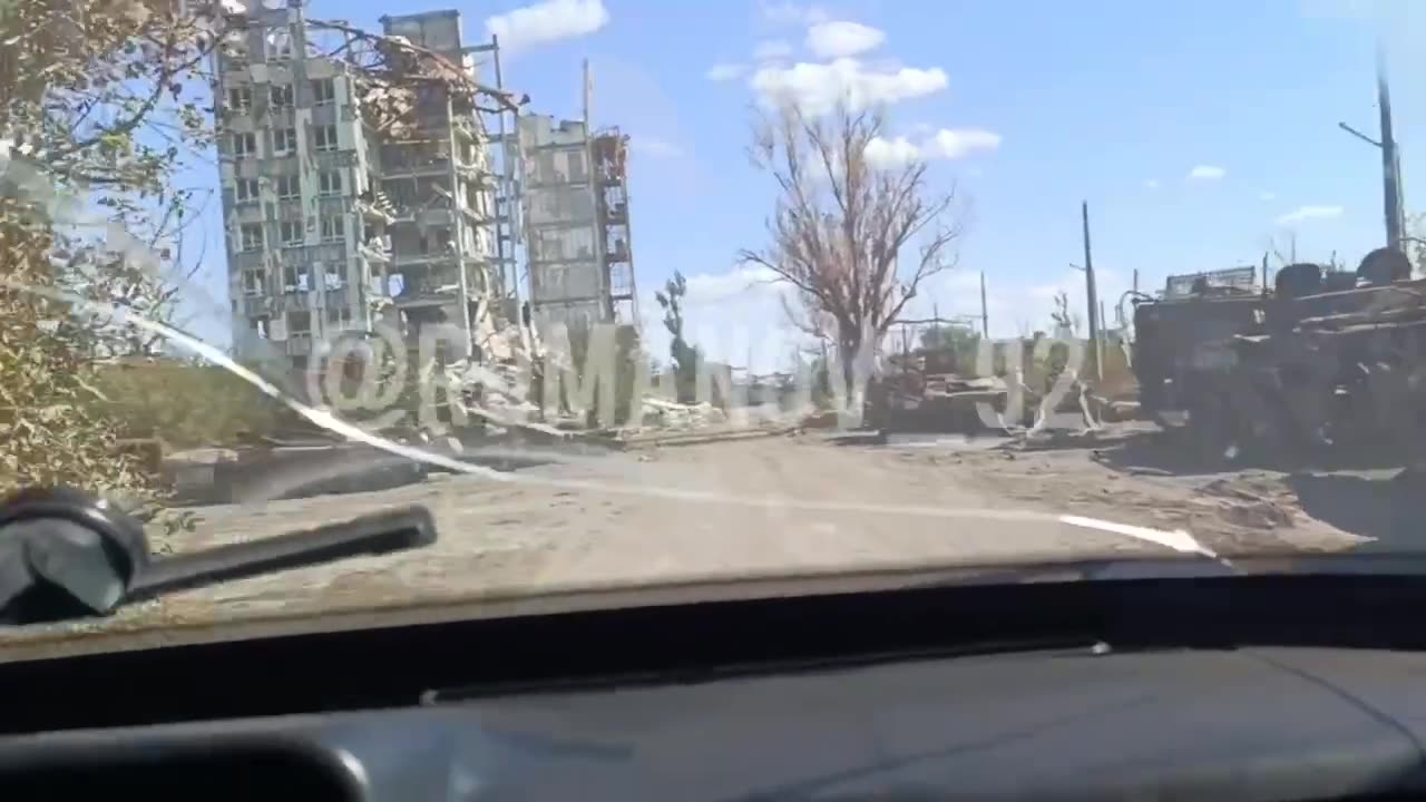 Russian soldiers drive past a huge amount of destroyed armored vehicles,