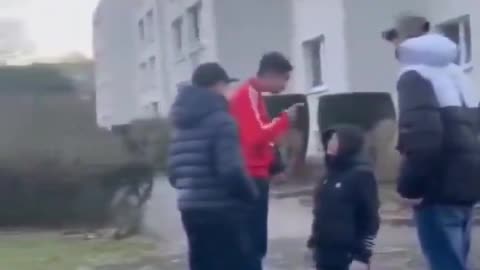The fake asylum seekers threaten and beat a shy German boy who is forced to kneel.
