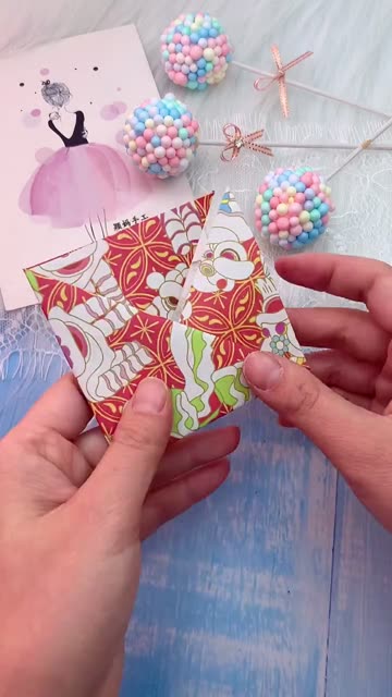 Hands Folding Traditional Red and Gold Cloud Patterned Paper