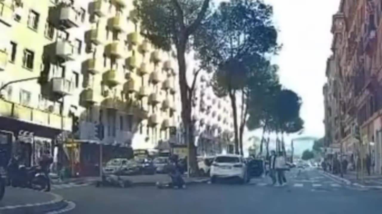 A rider crosses an intersection in Rome when the traffic light is red.