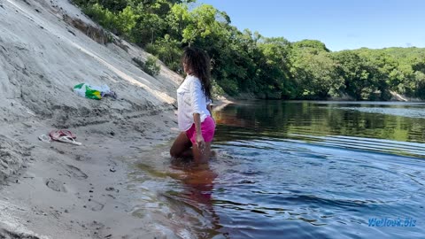 Wetlook girl fully dressed in a dress and shirt as she swims in the river