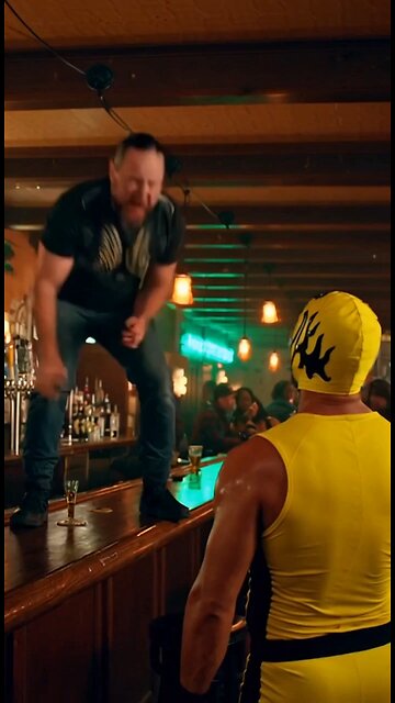 Russell Blade jumps off a bartender's table and clothes lines a yellow mask wrestler at a bar.