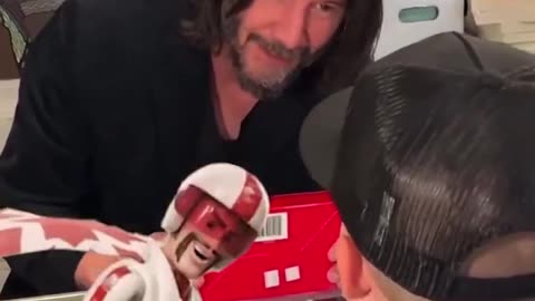 Keanu Reeves converses with a young fan