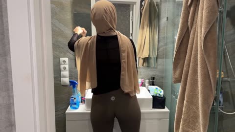 Wiping Bathroom Mirror in Hijab